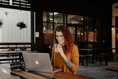 Mujer sonriente trabajando en laptop en cafetería moderna