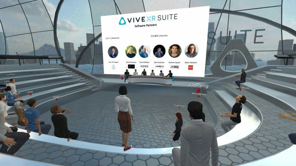 A virtual meeting space in HTC Vive with various avatars sitting in a semicircle watching an online event on a screen.