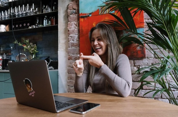 Lachende Frau am Laptop in modernem Café.