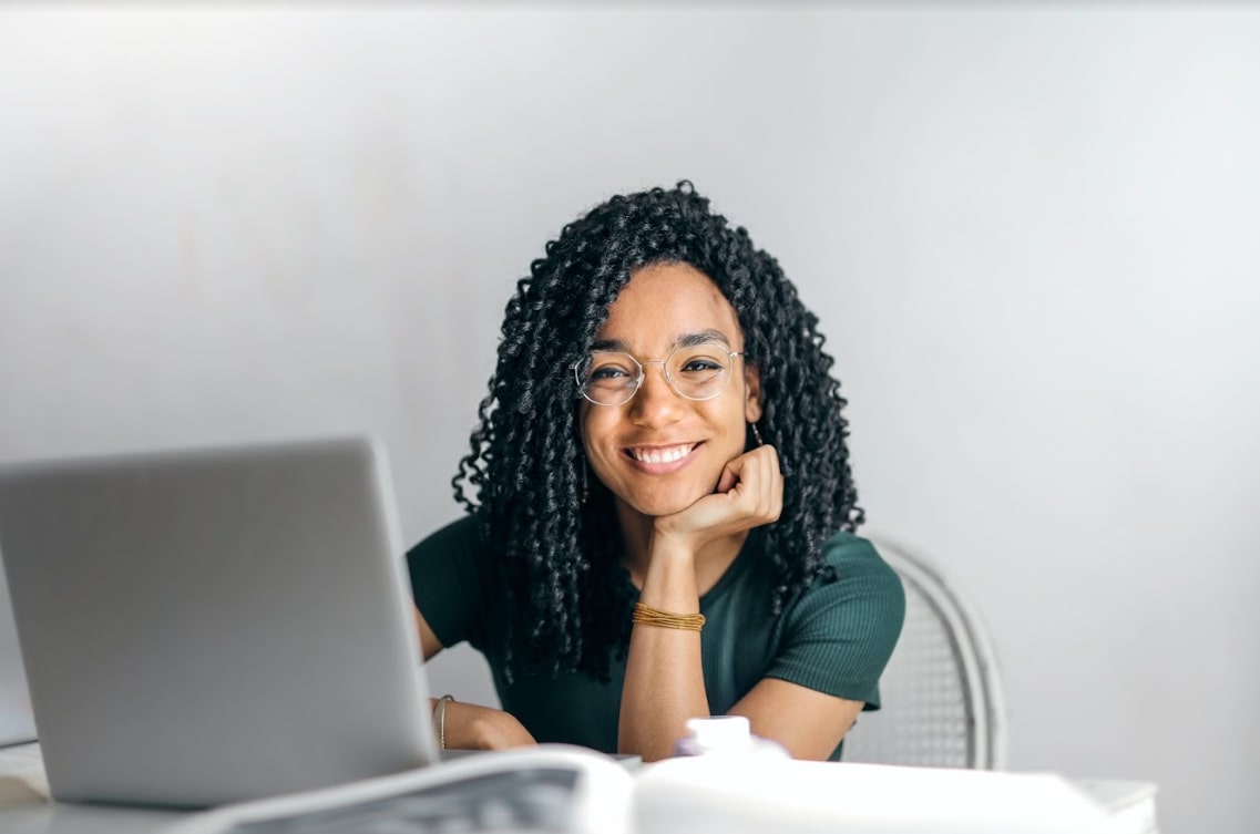 Woman sitting at a table with her laptop in front of her as she attends a virtual recruitment event