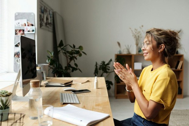 Frau klatscht an Schreibtisch im Homeoffice