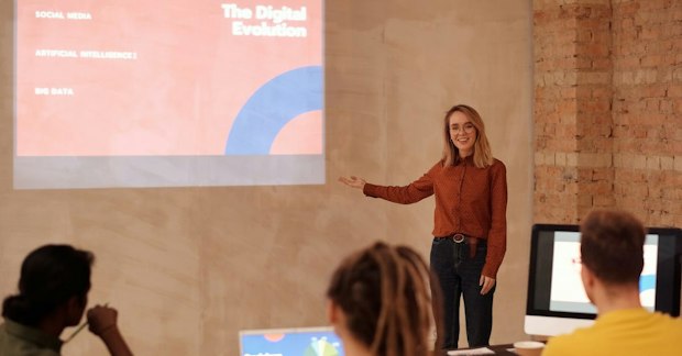 A Woman in Red Long Sleeve Shirt Giving a Presentation During a Seminar