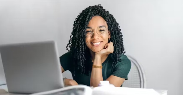 Lächelnde Frau mit Brille am Laptop