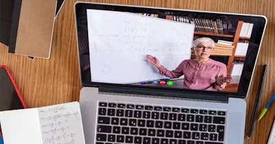 la pantalla de un portátil muestra a un profesor dando una clase virtual