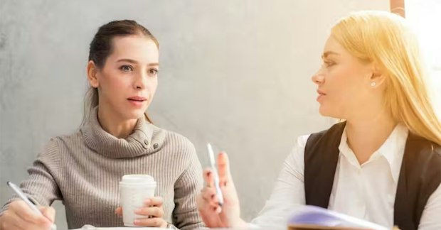 two blonde women discussing communication in the workplace