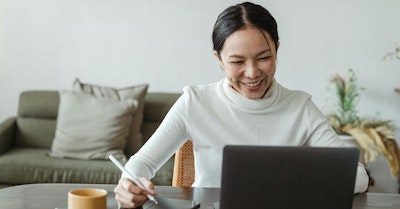 Mujer sonriente trabajando en laptop en casa