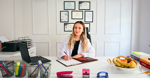 Mujer nutricionista en oficina con frutas y laptop
