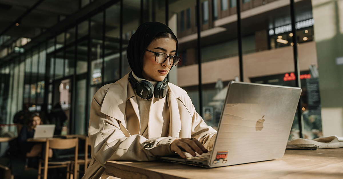 Frau mit Hijab arbeitet am Laptop im Café