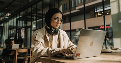 Frau mit Hijab arbeitet am Laptop im Café