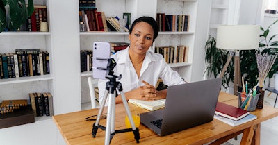 Mujer grabando video con laptop y libro en oficina