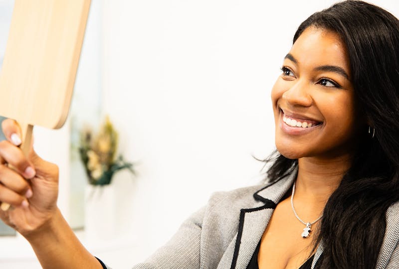 woman looking at hand mirror