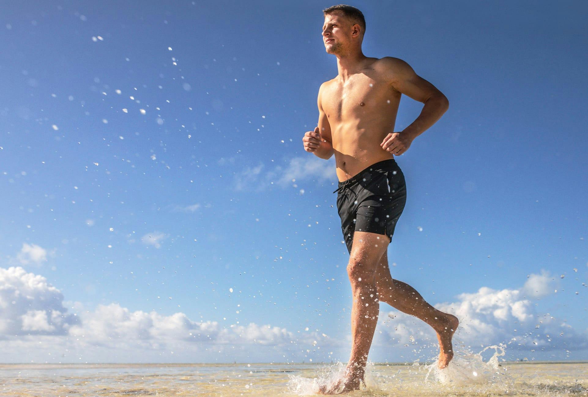 Man running on the beach shirtless