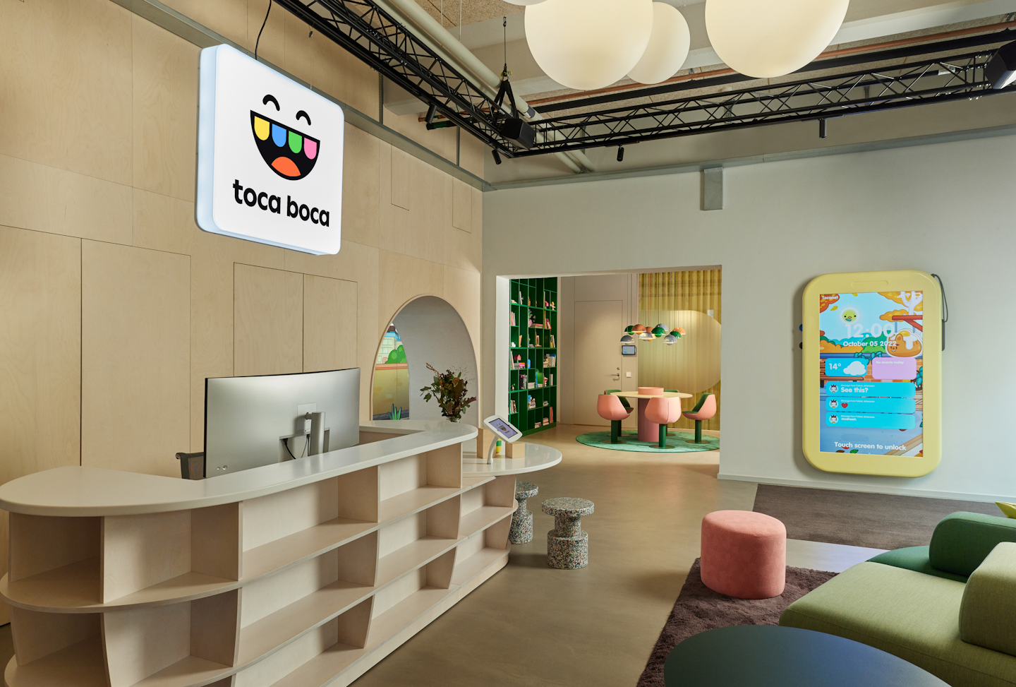 This is a photo of the entrance of Toca Boca Campus. This space is called Rob-o-cafe and there is a large phone decoration on the wall with some playful things for people to do. The Toca Boca logo is hanging above the reception desk