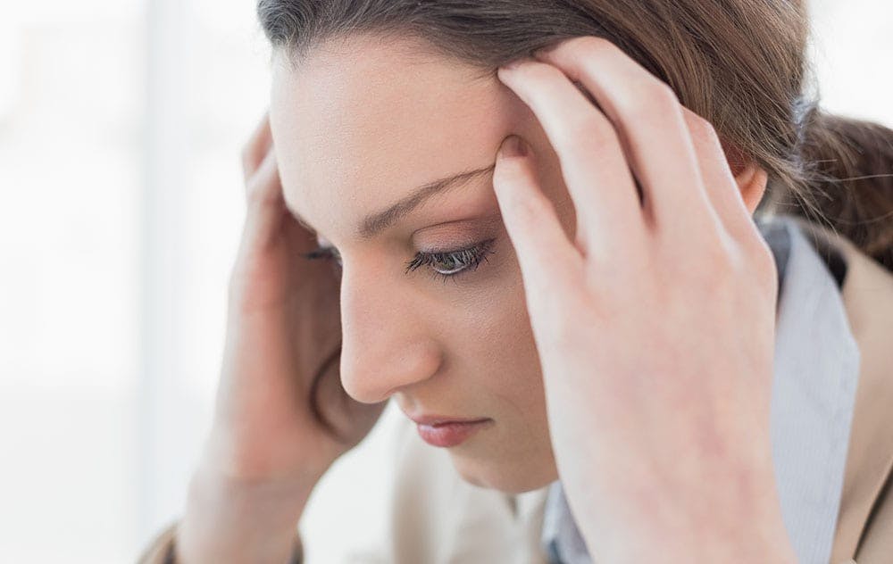 woman holding on to her head