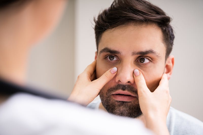 woman pressing on man's sinuses