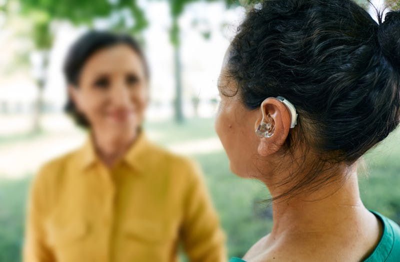 woman with hearing aid talking to another woman