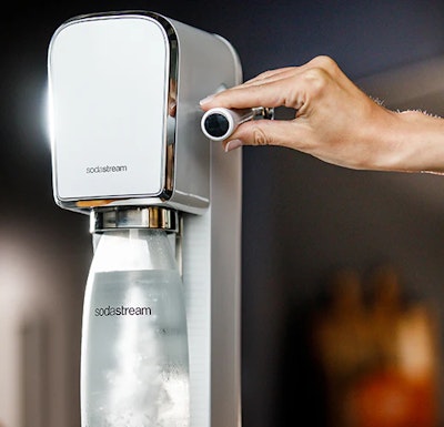 Kobieca ręka uruchamia ekspres SodaStream
