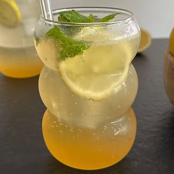 Lemoniada z syropem z czarnego bzu i cytryn "Elderflower lemonade" przyozdobiona plasterkiem cytryny i miętą
