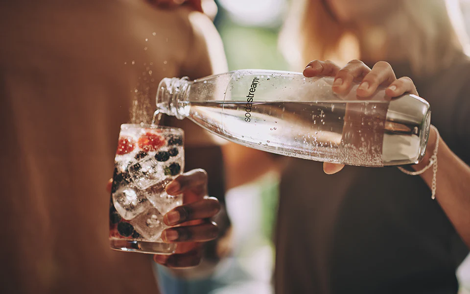 Nalewanie wody gazowanej SodaStream z butelki do szklanki - zdjęcie.