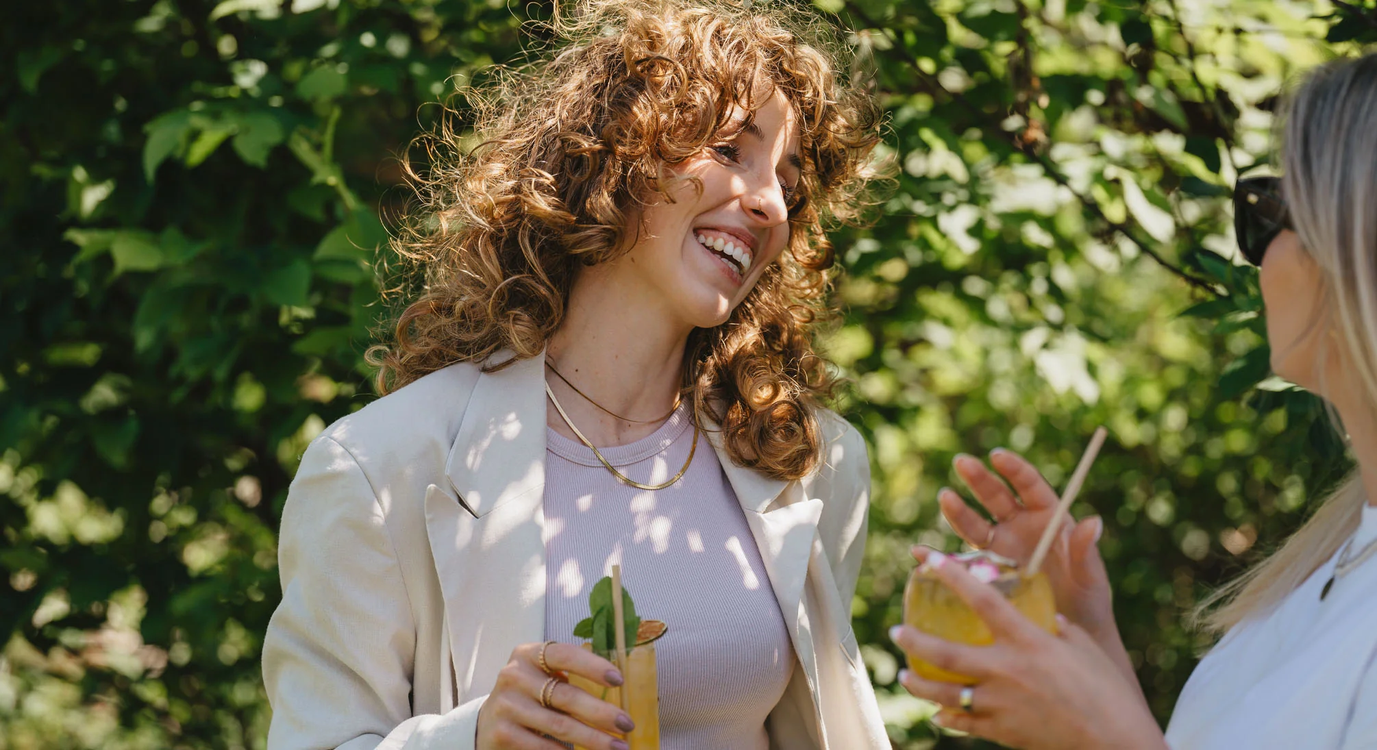 Uśmiechnięte kobiety z drinkami w dłoniach na garden party.