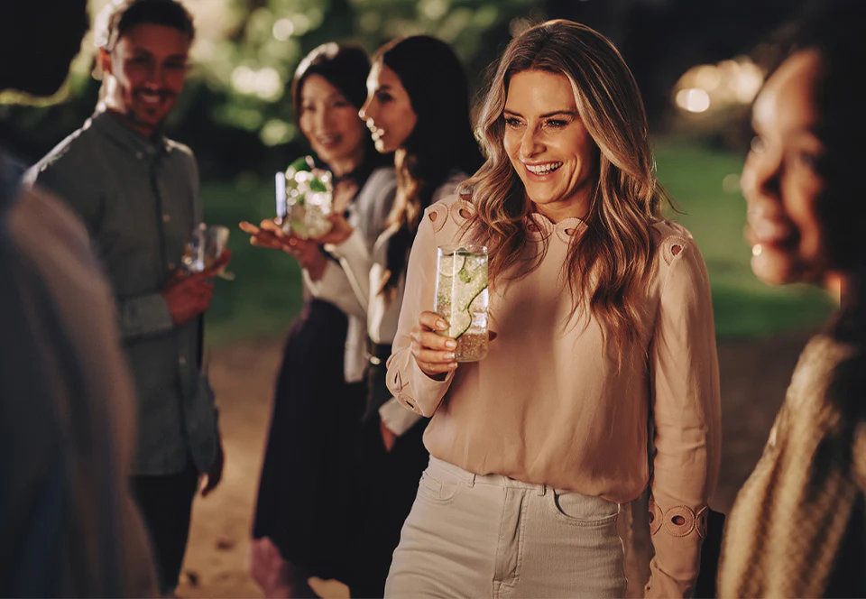 Uśmiechnięta kobieta z drinkiem na garden party