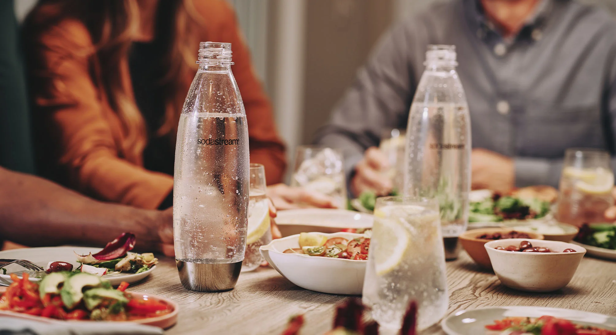 Wielorazowe ekologiczne butelki Sodastream z wodą gazowaną stojące na stole pośród posiłków