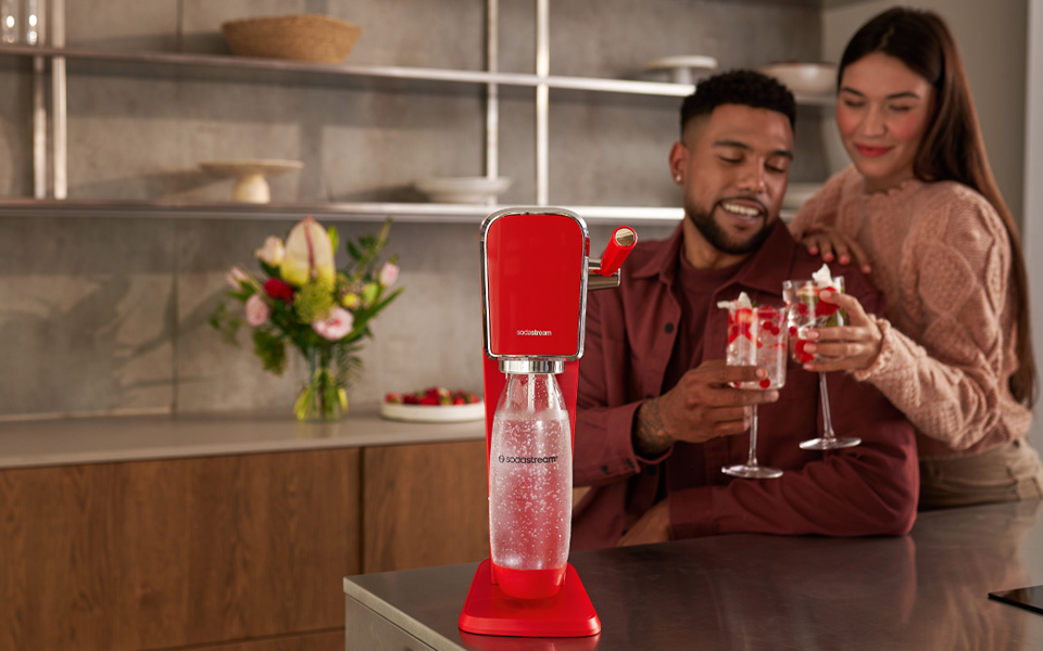 Uśmiechnięta para z drinkami i saturator SodaStream Art - czerwony