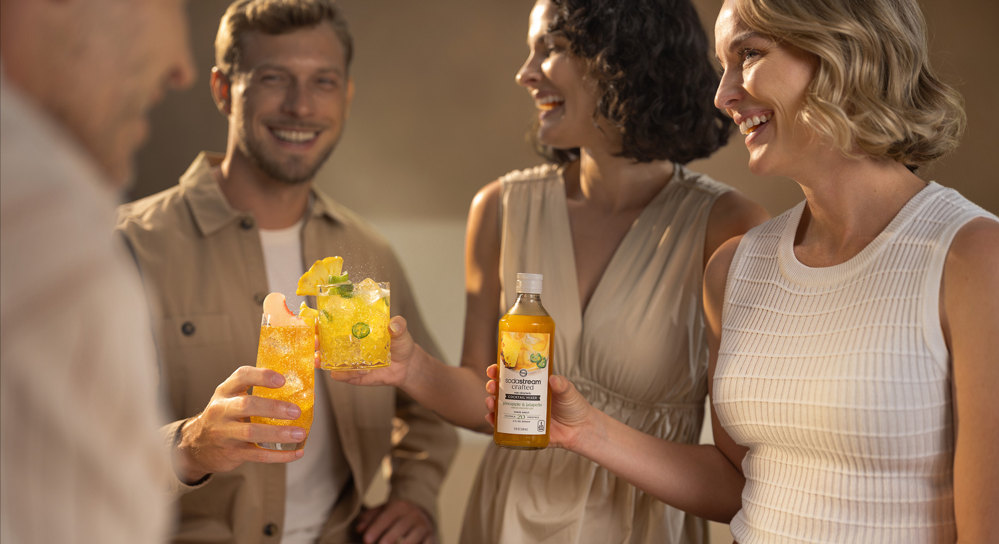 Grupka uśmiechniętych przyjaciół przy mocktailach z syropem SodaStream crafted