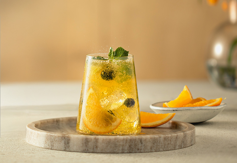 Mocktail w przezroczystej szklance z plastrami pomarańczy i kostkami lodu. - zdjęcie