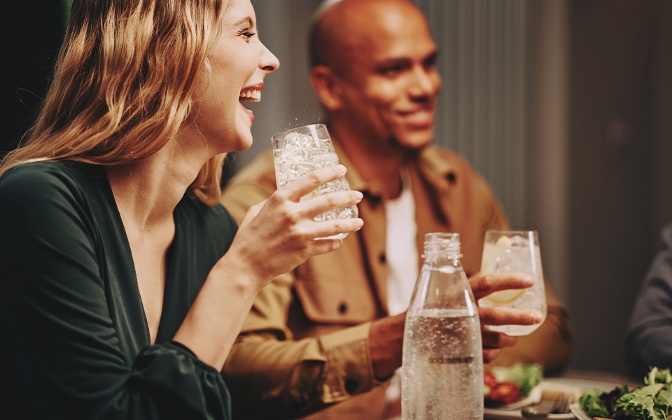 Uśmiechnięta kobieta ze szklanką wody gazowanej SodaStream