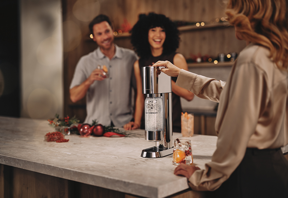 Kobieta gazująca wodę w saturatorze SodaStream Enso - zdjęcie.