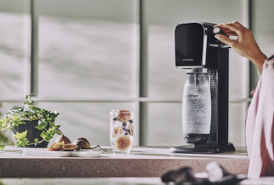 Kobieta gazuje wodę w czarnym saturatorze do wody SodaStream Art.