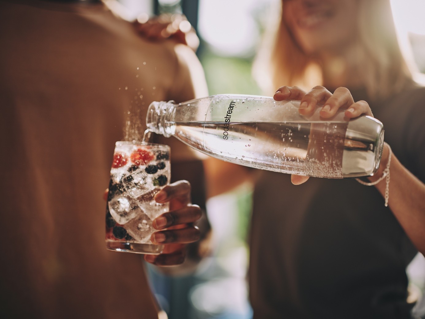 Kobieta na przyjęciu zero waste nalewa wodę gazowaną w saturatorze SodaStream do szklanki.