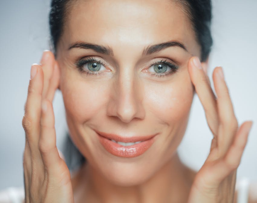 Woman looking into camera touching face