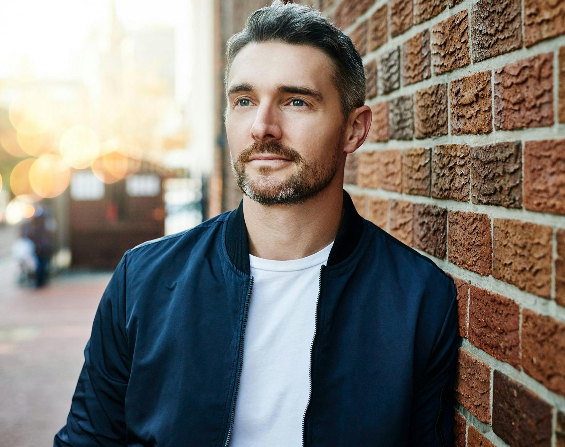 Man leaning against brick wall