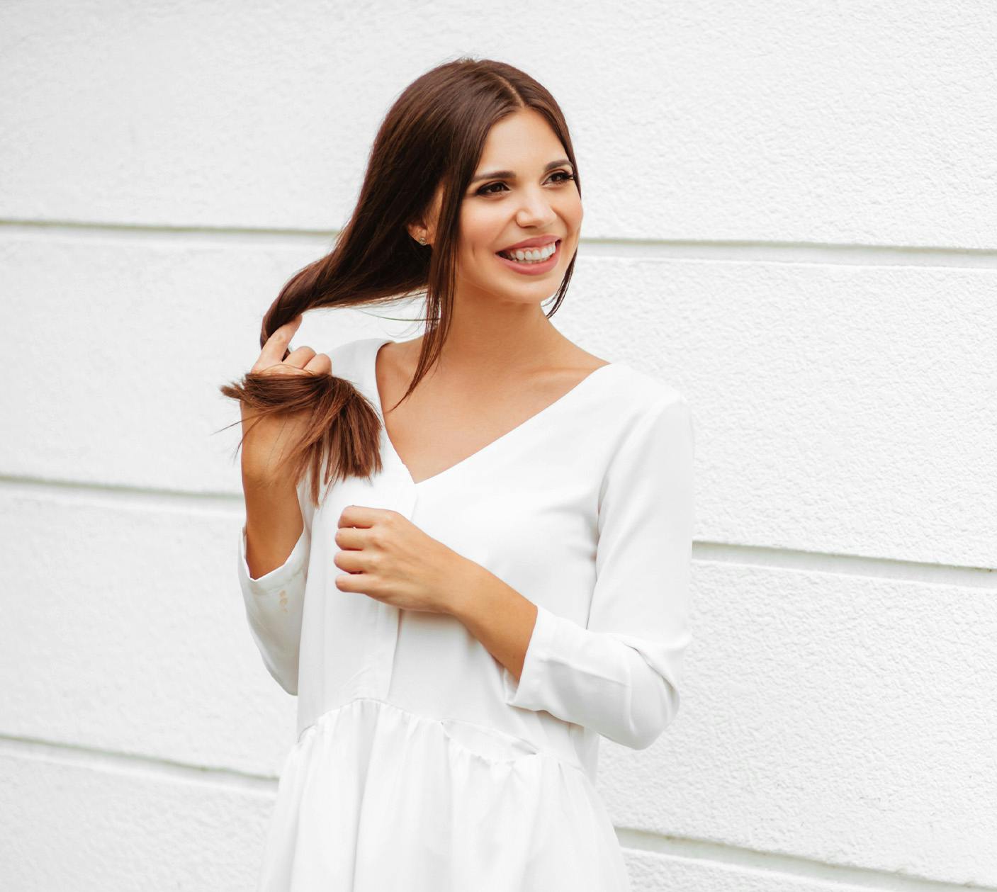 Woman in white next to white wall