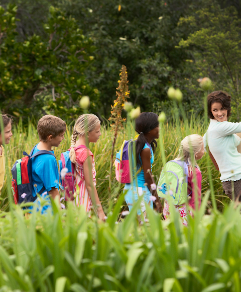 Young students in a field with teacher on school trip