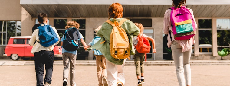 School kids running into school with bags