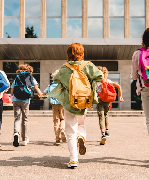School kids running into school with bags