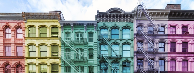 Exterior view of traditional New York apartment buildings that are painted to resemble a rainbow