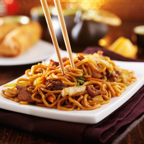 Close-up of noodle stir fry on a plate with chopsticks
