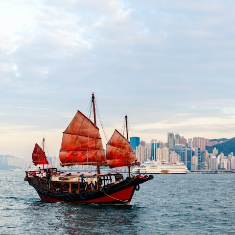 Chinese red-sail junk boat cruising along Sham Chun river in Hong Kong