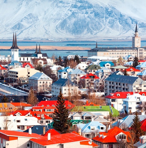 View of Reykjavík town with colourful buildings in front of snow capped mountains
