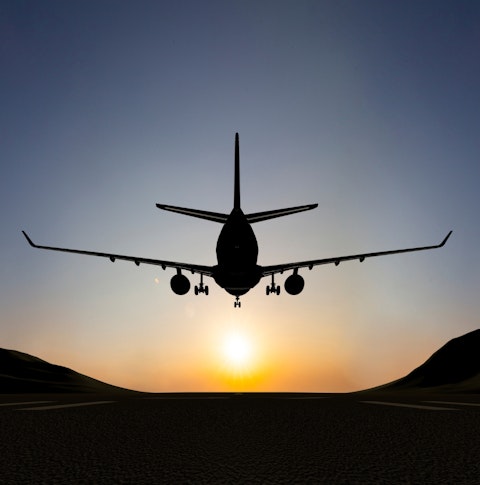 Plane landing on runway at sunrise