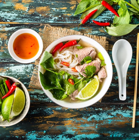Traditional Vietnamese soup Pho bo with herbs, meat, rice noodles, broth. Pho bo in bowl with chopsticks, spoon