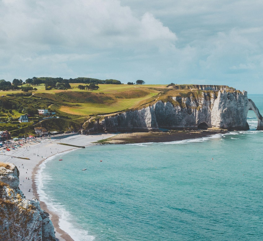 A view of the Normandy coastline with white cliffs and grey sandy beaches at daytime