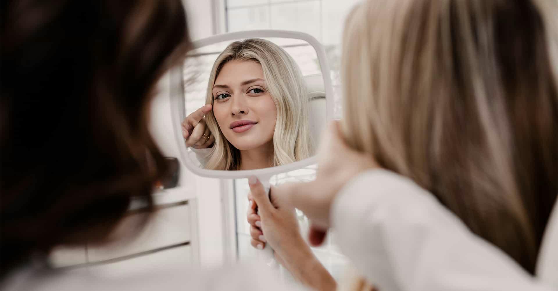 A woman looking at her face in a mirror