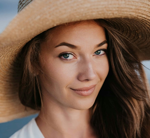 woman side profile smiling to the camera wearing a hat