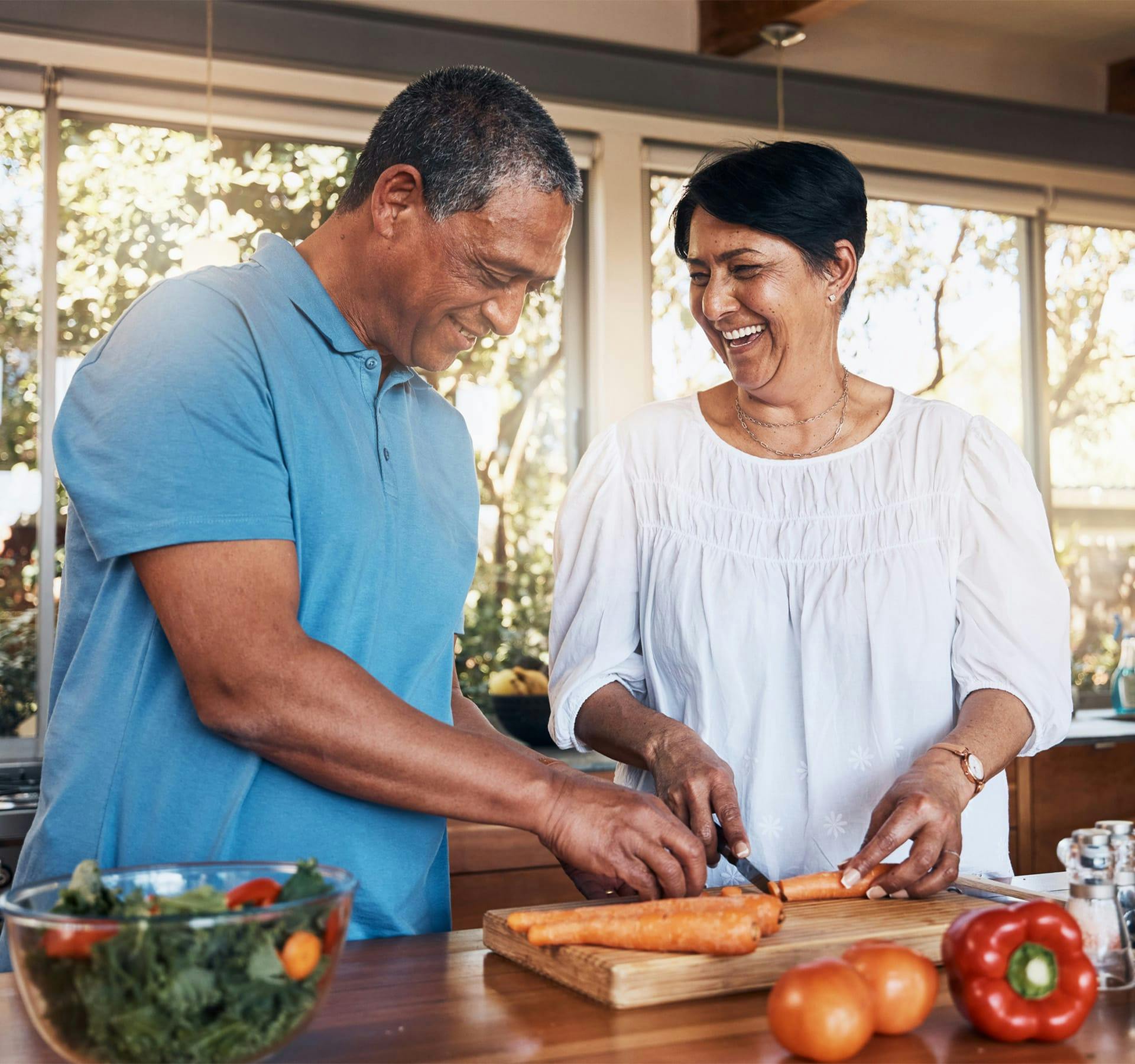 man and woman chopping carrots together
