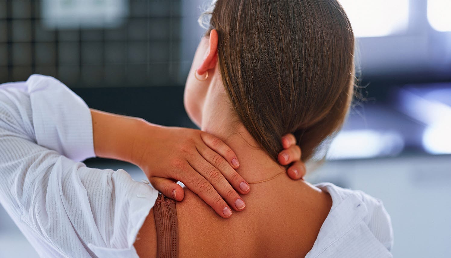 woman holding the back of her neck